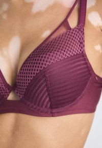 Mauve bralette with mesh panel and textured cups. Features multi-directional stripes, adjustable straps, and a soft, stretchy material.