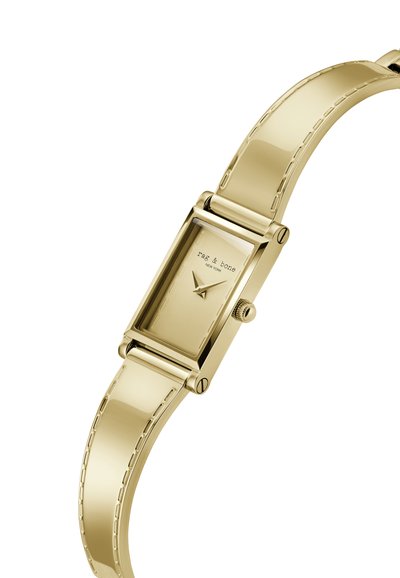 Guldtonet rektangulær urskive med glat metalsnor, minimalistisk urskive og en krone på siden. Funktioner mærkenavnet: "rag & bone."