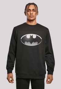 Felpa nera in misto cotone, con un grande logo di Batman a pois bianchi sul davanti. Collo rotondo classico e polsini a costine.