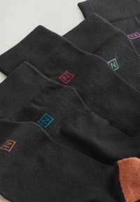 Mustat sukat, joissa on värikkäitä neliönmuotoisia logokoristeita: punainen, vaaleanpunainen, sininen ja ruskea. Sukissa on resorikuvio ja erilaiset varresävyt.