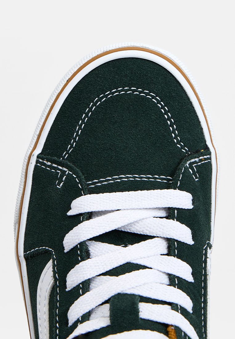 Grüne Wildledersneaker mit weißen Schnürsenkeln, weißen Nähten und Gummisohle. Abgerundete Zehe und kontrastierende beige Akzente an der Sohle.