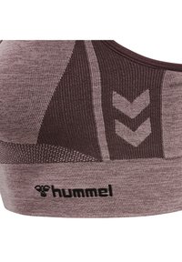 Brązowy sportowy biustonosz w paski, wykonany z teksturowanej tkaniny. Posiada wzór w zygzak, logo Hummel oraz szeroki elastyczny pasek na dole.