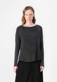 Tamsiai pilkos spalvos ilgomis rankovėmis, apvalaus kaklo viršus, pagamintas iš švelnios medžiagos. Savybės: nesuišyta apdaila ir tekstūruotas paviršius, derinamas su plačiu juodu sijonu.