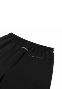 Zwarte sportbroekjes met een elastische tailleband, voorzien van een subtiel logo, een grijze accentdetail en een gladde stoftextuur.