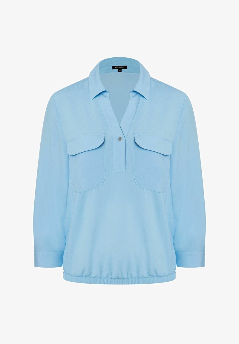 Blouse bleu clair à manches longues avec col, deux poches poitrine à rabat, une demi-patte de boutonnage pressionnée et un ourlet élastique.