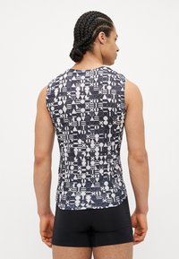 Ärmelloses Sportshirt mit einem geometrischen schwarz-weißen Muster, eng anliegendem Design und Rundhalsausschnitt. Hergestellt aus leichtem Stoff.