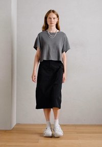 Gray cropped t-shirt with short sleeves, paired with a black midi skirt and white clogs. Simple design with no visible patterns or accents.