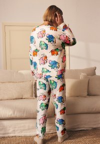 Pižama iš minkštos medžiagos, su spalvingu dramblių raštu rožinės, mėlynos, žalios ir oranžinės spalvų. Ilgomis rankovėmis ir elastine liemene.