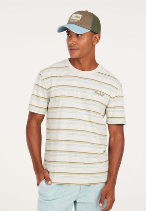 Gestreiftes T-Shirt in hellem Beige mit gelben und blauen Streifen sowie einem kleinen Logo. Kombiniert mit einer braunen und hellblauen Mütze.