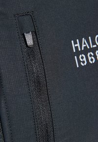 Schwarze, mit einem Reißverschluss ausgestattete Jacke mit glatter Textur. Merkmale eines kontrastierenden "HALO 1968"-Grafiks in Weiß. Der Reißverschluss ist schwarz mit einem strukturierten Zug.