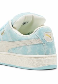 Kék velúr sneaker fehér bőr részletekkel, texturált gumitalppal, párnázott bokarésszel és arany logóval a sarkán. Koptatott kivitel a kéken.