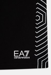 Camisa preta com um design geométrico branco de um lado. Logótipo branco "EA7 EMPORIO ARMANI" impresso na parte inferior. Tecido com textura suave.
