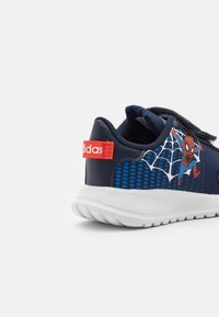 Baskets bleu marine avec un dessus texturé, présentant un graphique de Spider-Man, des accents rouges et une semelle extérieure blanche moulée. Sangle Velcro incluse.