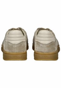 Beige Wildlederschuhe mit glatten Lederakzenten, strukturierten Gummisohlen und genähten Details an der Ferse. Mit einem flachen Design.