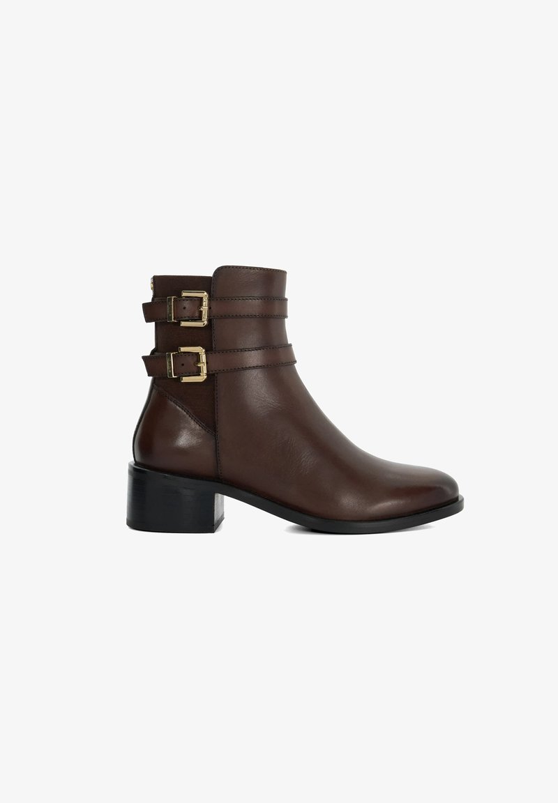Botte chelsea en cuir marron avec deux sangles décoratives et boucles dorées, bout arrondi et un petit talon bloc pour plus de stabilité.