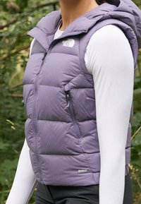 Fioletowa pikowana kamizelka z kapturem, wyposażona w przedni zamek błyskawiczny, boczną kieszeń oraz lekki materiał. Na dolnym prawym rogu oznaczona napisem "550".