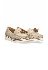 Mocasines beige con diseño perforado, puntera redonda, detalles de borlas y suela texturizada blanca; los materiales incluyen ante y goma.