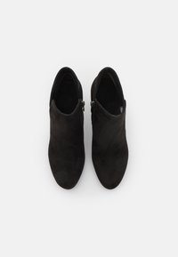 Schwarze Wildleder-Ankle Boots mit schlankem Design, spitzer Zehenform und zwei seitlichen Reißverschlüssen für einfachen Einstieg. Glatte Textur ohne sichtbare Muster.