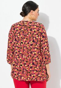 Blusa nera con motivo floreale e di uccelli colorati, maniche a tre quarti, scollatura tonda e vestibilità rilassata.