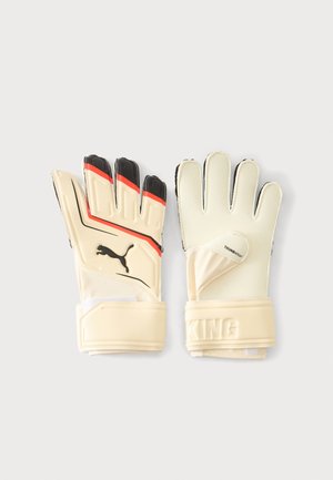 Ζευγάρι μπεζ γάντια τερματοφύλακα Puma με μαύρες και κόκκινες λεπτομέρειες, με ρυθμιζόμενους ιμάντες καρπού και ετικέτα "THUMBWRAP" σε ένα γάντι.