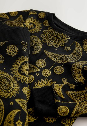 Musta kangas, jossa on monimutkaisia kultaisia taivaallisia kuvioita, kuten kuita, tähtiä ja mandalamaisia kukkakuvioita, ja varustettu resorireunuksilla hihansuissa ja kaula-aukossa.