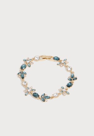 Bracelet en or avec des pierres précieuses bleues et claires alternées, disposées en grappes florales sur un fond clair.