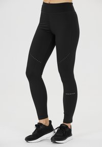 Svarta sportleggings i stretchmaterial med hög midja, dekorativa prickmönster på låren och en logotyp vid vristen.