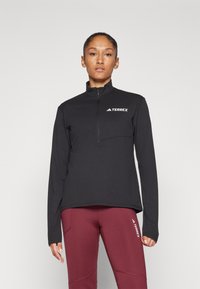 Pullover nero con mezza zip e maniche lunghe, dotato di tasca frontale e logo bianco "TERREX" sul petto. Design leggero e sportivo.