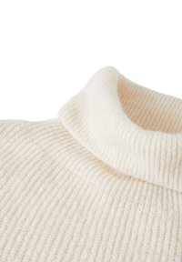 Cremfarbener gerippter Rollkragenpullover mit weicher, flauschiger Textur, Nahaufnahme des Kragens und des oberen Brustbereichs.