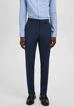 Pantalons ajustés bleu marine avec une texture lisse, dotés de passants de ceinture, de poches avant et d'un design à jambe droite. Portés avec une chemise bleu clair.