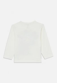 Hvit langermet skjorte med rund hals og myk tekstur. Har et falmet grafisk mønster på ryggen.