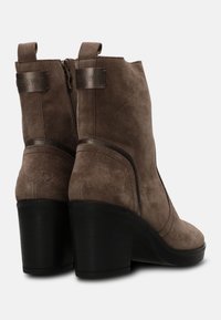 Stivaletti alla caviglia in suede marrone con una finitura testurizzata, dotati di un tacco spesso nero, zip sul retro e dettagli ad anello nella parte superiore.