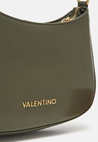 Bolso de mano verde oliva, brillante, con una forma estructurada, logo dorado de "Valentino" y cierre de cremallera. Textura lisa con costuras en contraste.
