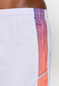 Weiße Sportshorts mit farblich verlaufenden lila und orangefarbenen Seitenpaneelen, ausgestattet mit einem strukturierten Stoff und einem kontrastierenden Ziernahtdetail entlang der Naht.