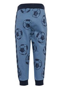 Blå joggbyxor med ett upprepande mönster av svarta fotbollar. Har ett marinblått elastiskt midjeband och anklar. Mjukt bomullsmaterial.