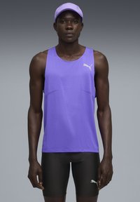 Camiseta atlética sin mangas de color púrpura, hecha de un tejido transpirable, combinada con pantalones cortos negros. Presenta el logo de Puma y un corte estructurado.