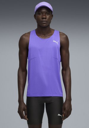 Camiseta atlética sin mangas de color púrpura, hecha de un tejido transpirable, combinada con pantalones cortos negros. Presenta el logo de Puma y un corte estructurado.