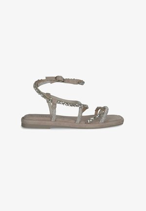Beige flache Sandalen mit mehreren dünnen Riemen, von denen einige mit silbernen Verzierungen versehen sind, und einem Schnallenriemen zur Unterstützung des Knöchels.