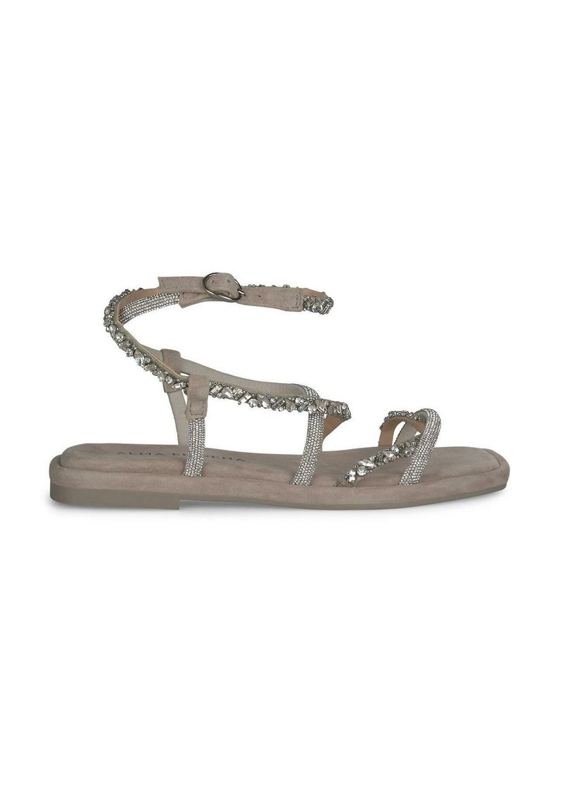 Beige platte sandalen met meerdere dunne bandjes, sommige versierd met zilveren versieringen, en een gespband voor ondersteuning van de enkel.