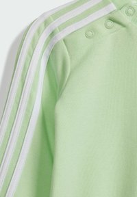 Maglione di cotone verde chiaro con strisce bianche sulle spalle, dotato di bottoni a pressione e texture morbida. Design casual con scollatura rotonda.