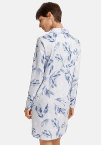 Vestito azzurro chiaro con un motivo a foglia in blu scuro, dotato di colletto e maniche lunghe. Il tessuto è morbido con una leggera lucentezza.