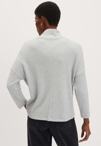 Maglione grigio chiaro con maniche lunghe, colletto alto e vestibilità rilassata. Caratterizzato da una texture morbida e un dettaglio con cucitura centrale sul retro.