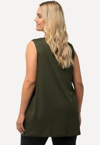 Top senza maniche verde oliva realizzato in morbido tessuto, con una vestibilità rilassata, scollatura rotonda e spacchi laterali per facilitarne i movimenti.
