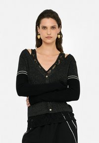 Cardigan nero a maglia con texture lucida, dettagli in pizzo, scollatura a V, due bottoni e maniche lunghe con polsini a strisce bianche. Dettaglio in pizzo all'orlo.