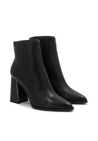 Botas de tobillo negras en cuero liso con punta afilada y tacón ancho. Incluyen una cremallera lateral y un sutil acento metálico con el logo.