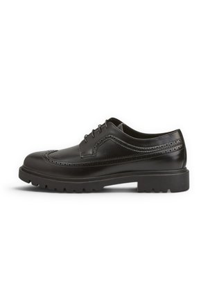 Scarpa brogue in pelle nera con design wingtip, perforazioni, chiusura frontale con lacci e suola spessa e testurizzata.