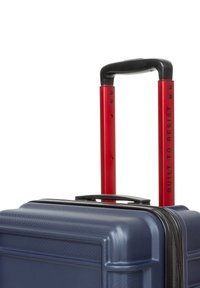 Hårdkantad resväska i marinblått med en strukturerad yta, säker dragkedja och röd teleskophandtag med texten "BUILT TO RESIST" i svart.