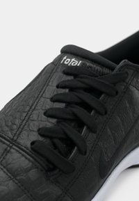 Μαύρο αθλητικό παπούτσι με υφασμάτινο επάνω μέρος από δέρμα, μαύρα κορδόνια, διακριτικό λογότυπο και λευκή εξωτερική σόλα από καουτσούκ. Διαθέτει ομαλό περιλαίμιο και ραμμένες λεπτομέρειες.