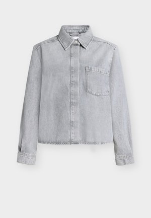 Chemise en denim gris clair avec col boutonné, poche poitrine unique, manches longues et ourlet raccourci avec détails de coutures.