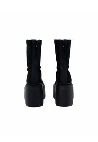 Stivali neri in suede con design flat, cerniera sul retro e suola platform a guscio. Texture liscia e silhouette slanciata.